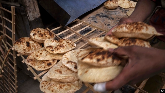 A worker collects Egyptian traditional 'baladi' flatbread, at a bakery, in el-Sharabia, Shubra district, Cairo, Egypt, Wednesday, March 2, 2022. (AP Photo/Nariman El-Mofty)