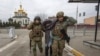 Dua prajurit Ukraina memapah seorang perempuan lansia di kota Irpin, Ukraina, Minggu, 6 Maret 2022. (AP Photo/Andriy Dubchak, File)