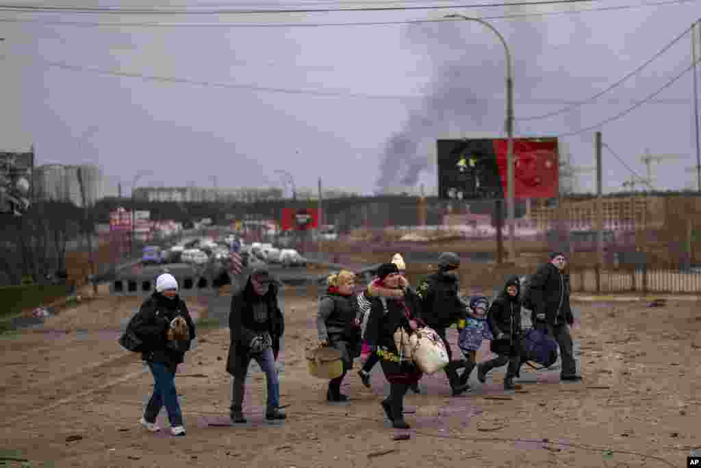 A Ukrainian police officer helps people as artillery echoes nearby while fleeing Irpin in the outskirts of Kyiv, March 7, 2022. Russia announced yet another cease-fire and a handful of humanitarian corridors to allow civilians to flee Ukraine.