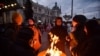 People fleeing Russia's invasion of Ukraine warm up by a fire barrel near the train station, in Lviv, Ukraine, March 10, 2022. 