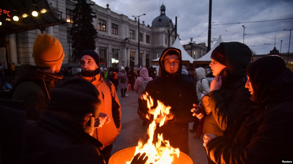 Las personas que huyen de la invasión rusa de Ucrania se calientan junto a un barril de fuego cerca de la estación de tren, en Lviv, Ucrania, el 10 de marzo de 2022.