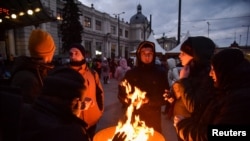 People fleeing Russia's invasion of Ukraine warm up by a fire barrel near the train station, in Lviv, Ukraine, March 10, 2022. 