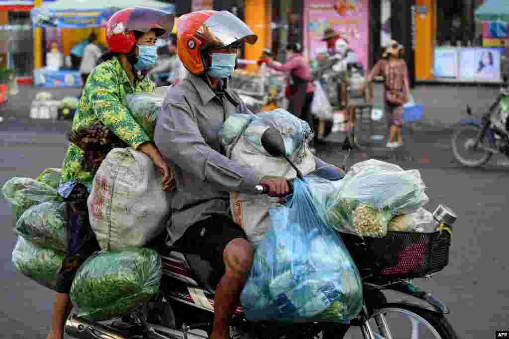 A couple transports vegetables on a motorcycle in Phnom Penh, Cambodia.