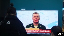 Para warga tampak menyaksikan siaran berita mengenai konflik Rusia dan Ukraina di salah satu pusat perbelanjaan di Hangzhou, Provinsi Zhejiang, pada 25 Februari 2022. (Foto: AFP)