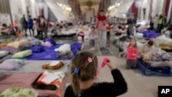 A child refugee who fled the Russian invasion from neighboring Ukraine plays with a soap bubble toy inside a ballroom converted into a makeshift refugee shelter at a 4-star hotel & spa, in Suceava, Romania, Friday, March 4, 2022. (AP Photo/Andreea Alexandru)