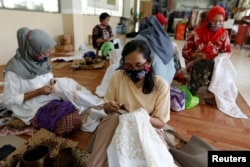 Para perempuan tampak mengenakan masker saat membatik di salah satu workshop di Jakarta, pada 1 Juli 2020. (Foto: Reuters/Willy Kurniawan)