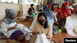 Para perempuan tampak mengenakan masker saat membatik di salah satu workshop di Jakarta, pada 1 Juli 2020. (Foto: Reuters/Willy Kurniawan)