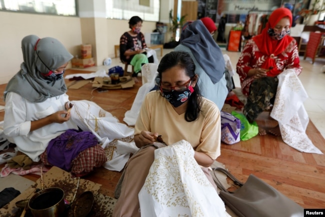 Para perempuan tampak mengenakan masker saat membatik di salah satu workshop di Jakarta, pada 1 Juli 2020. (Foto: Reuters/Willy Kurniawan)