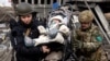 A baby is evacuated as people flee near a destroyed bridge to cross Irpin River as Russia's invasion on Ukraine continues, in Irpin outside Kyiv, March 9, 2022. 