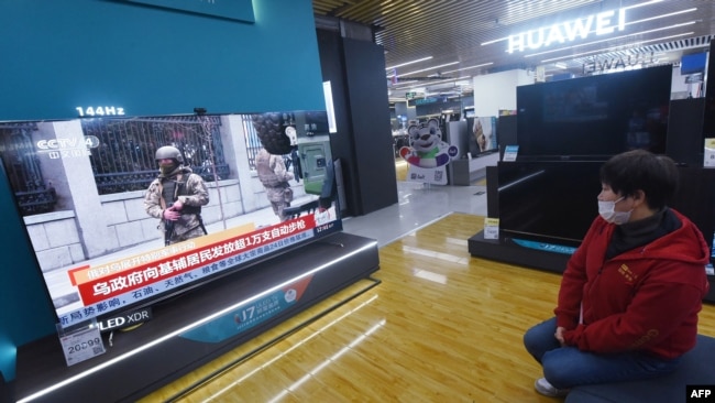 A resident watches a TV screen showing news about conflict between Russia and Ukraine at a shopping mall in Hangzhou, in China's eastern Zhejiang province on February 25, 2022. (Photo by AFP)