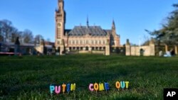 Candles are set in the grass with the text 'Putin Come Out' in front of the International Criminal Court in The Hague, Netherlands, March 7, 2022.
