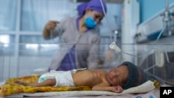 FILE - A nurse takes care of a baby in the neonatal intensive care unit of Malalai Maternity hospital in Kabul, Afghanistan, Dec. 9, 2021.