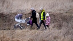 Una mujer con su bebé camina con otras personas que huyen de Ucrania, en el cruce fronterizo de Medyka, Polonia.