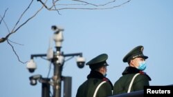 Anggota polisi paramiliter yang mengenakan masker pelindung berdiri di dekat kamera pengintai di Bund, menyusul kasus baru COVID-19, di Shanghai, Cina 20 Januari 2022. (Foto: REUTERS/Aly Song)