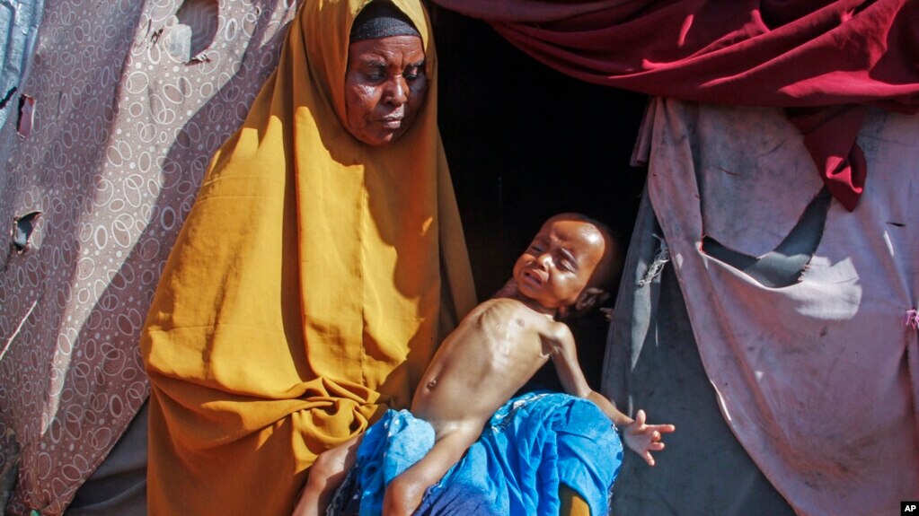 FILE - Boolo Aadan, 63, who fled drought-stricken areas, holds her 9 month old grandchild outside the tent where they now live at a makeshift camp on the outskirts of Mogadishu, Somalia, on Feb. 4, 2022.