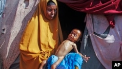 FILE - Boolo Aadan, 63, who fled drought-stricken areas, holds her 9 month old grandchild outside the tent where they now live at a makeshift camp on the outskirts of Mogadishu, Somalia, on Feb. 4, 2022. 