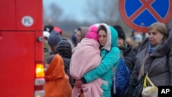 FILE - Refugees, mostly women with children, wait for transportation at the border crossing in Medyka, Poland, March 5, 2022, after fleeing from the Ukraine.