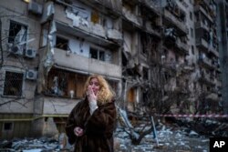 Reaksi Natali Sevriukova di samping rumahnya menyusul serangan roket di kota Kyiv, Ukraina, Jumat, 25 Februari 2022. (Foto: AP/Emilio Morenatti)