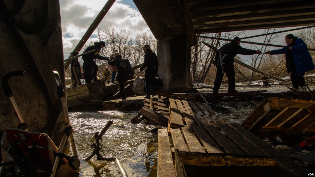 Civilians in Irpin escape from the battles through an improvised path created alongside a bombed bridge by Ukrainian forces in Ukraine, March 8, 2022. (Yan Boechat/VOA) 