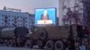 FILE - Police stand in preparation for a possible opposition rally as Russian President Vladimir Putin is seen on a television screen, in Khabarovsk, 6,100 kilometers (3,800 miles) east of Moscow, Russia, April 21, 2021.
