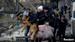 A man carries a dog as people flee, amid Russia's invasion of Ukraine, in Romanivka, Ukraine, March 9, 2022. 