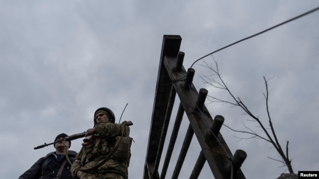 A service member of the Ukrainian armed forces stands by the only escape route used by locals to evacuate from the town of Irpin, after days of heavy shelling, while Russian troops advance towards the capital, March 7, 2022.