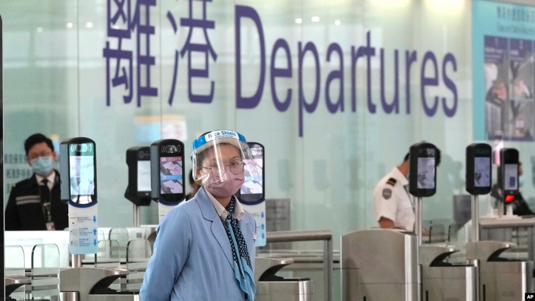 Seorang petugas bandara mengenakan masker dan pelindung wajah berjaga di dekat konter keberangkatan di bandara Hong Kong, 18 Februari 2022. (Foto: AP Photo/Kin Cheung)