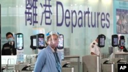 Seorang petugas bandara mengenakan masker dan pelindung wajah berjaga di dekat konter keberangkatan di bandara Hong Kong, 18 Februari 2022. (Foto: AP Photo/Kin Cheung)