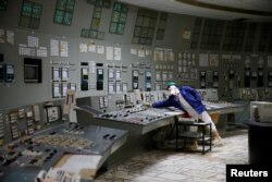 FILE - An employee is seen in a control center of one of the stopped reactors at the Chernobyl Nuclear Power Plant in Chernobyl, Ukraine, March 25, 2021.