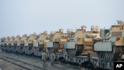 Servicemen of the "Fighting Eagles" 1st Battalion, 8th Infantry Regiment, walk by tanks that arrived via train to the US base in Mihail Kogalniceanu, eastern Romania, Feb. 14, 2017. 