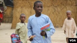 Un groupe d'enfants traverse les huttes du camp interne de personnes déplacées d'El-Miskin le 20 août 2020 à Maiduguri.