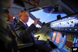 Russian President Vladimir Putin sits in the cockpit of an airplane simulator as he visits Aeroflot Aviation School outside Moscow, March 5, 2022.