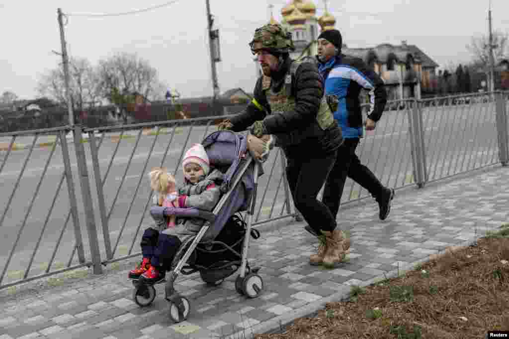 A service member of the Ukrainian armed forces helps to evacuate a child from the town of Irpin, March 7, 2022.