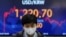 A currency trader walks near the screen showing the foreign exchange rate between U.S. dollar and South Korean won at a foreign exchange dealing room in Seoul, South Korea, Monday, March 7, 2022. (AP Photo/Lee Jin-man)