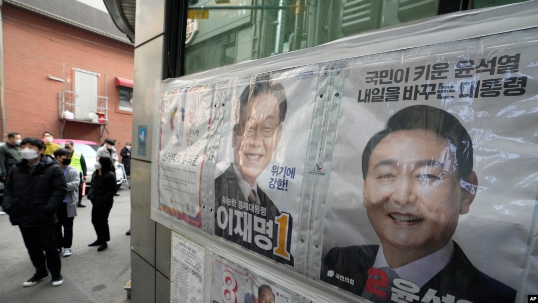Posters of presidential candidates of Lee Jae-myung of the ruling Democratic Party and Yoon Suk Yeol, right, of the main opposition People Power Party are displayed as people wait to cast their early votes for the March 9 presidential election, Seoul, March 4, 2022.