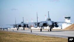 In this image provided by the US Air Force, US F-15E Strike Eagles taxi to their parking spots after completing a NATO mission out of Lask Air Base, Poland, Feb. 28, 2022.