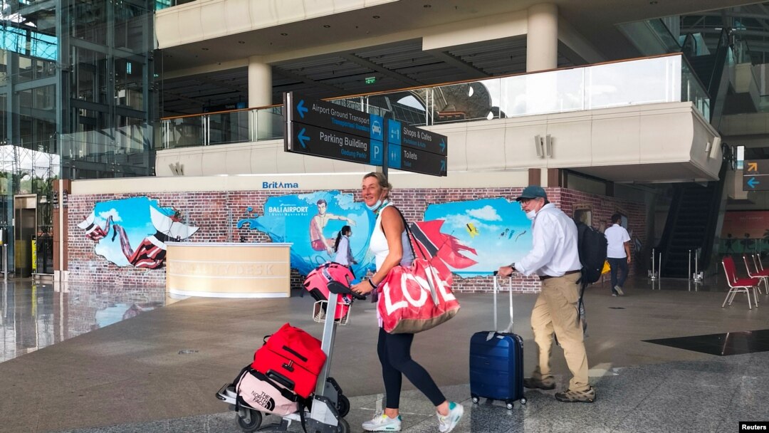 Turis asing membawa barang bawaan mereka setibanya di Bandara Internasional I Gusti Ngurah Rai, saat pemerintah setempat memulai hari pertama uji coba 'bebas karantina', di tengah pandemi COVID-19 di Bali, 7 Maret 2022. (REUTERS/Sultan Anshori)
