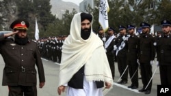 FILE - Taliban acting Interior Minister Sirajuddin Haqqani, center, reviews new Afghan police recruits during a graduation ceremony at the police academy in Kabul, Afghanistan, March 5, 2022. 