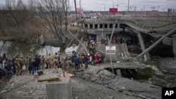  Người dân tìm đường băng qua cây cầu bị phá hủy bởi một cuộc không kích của Nga, trong khi rời đi khỏi thị trấn Irpin, Ukraine, ngày 5 tháng 3 năm 2022.
