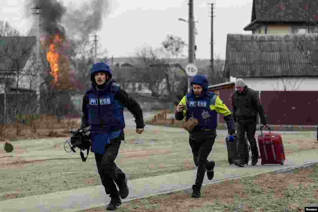 Journalists run for cover after heavy shelling by Russian troops in Irpin, March 6, 2022.
