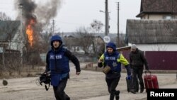 Journalists run for cover after heavy shelling on the only escape route used by locals, while Russian troops advance towards the capital, in Irpin, near Kyiv, Ukraine, March 6, 2022.