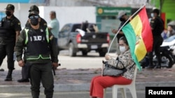 Foto de archivo de un oficial de policía hace guardia mientras un manifestante se sienta en la calle, en Santa Cruz, Bolivia, el 8 de noviembre de2021.