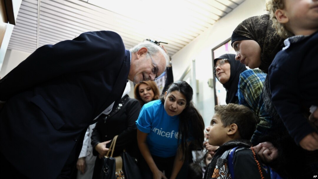 Tổng giám đốc UNICEF Anthony Lake (trái) nói chuyện với một bé trai đến một trung tâm y tế ở Damascus, Syria, để được uống vắc xin ngừa bại liệt, 29/10/13