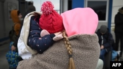 Una madre ucraniana sostiene a su hijo mientras espera en un puesto de control para ingresar a Rumania, después de cruzar el río Danubio en el cruce fronterizo de Isaccea-Orlivka entre Rumania y Ucrania el 26 de febrero de 2022.