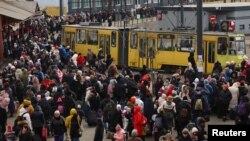 Refugees fleeing the ongoing Russian invasion of Ukraine wait for hours to board a train to Poland, outside the train station in Lviv, Ukraine, March 8, 2022. 