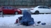 FILE - An Afghan woman holding her child begs on the snow-covered pavement in Kabul, Afghanistan, Jan. 27, 2022.