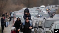 Refugiados ucranianos caminan junto a vehículos que se alinean para cruzar la frontera de Ucrania a Moldavia, el sábado 26 de febrero de 2022.