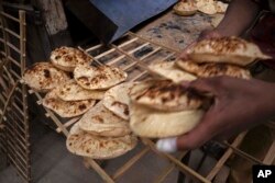 Seorang pekerja di sebuah toko roti, di el-Sharabia, distrik Shubra, Kairo, Mesir, mengumpulkan roti 'tradisional Mesir baladi', Rabu, 2 Maret 2022. Konflik Rusia-Ukraina berpotensi menciptakan kerawanan pangan dan membuat lebih banyak orang jatuh miskin di tempat-tempat seperti Mesir dan Lebanon, di mana makanan didominasi oleh roti yang disubsidi pemerintah. (Foto AP/Nariman El-Mofty)