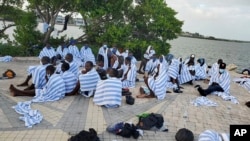 En imagen proporcionada por la Patrulla Fronteriza de Estados Unidos se muestran migrantes haitianos en la costa cubiertos con toallas luego que la embarcación de madera en que viajaran encalló frente a Key Largo, en los cayos de Florida, el 6 de marzo de 2022.