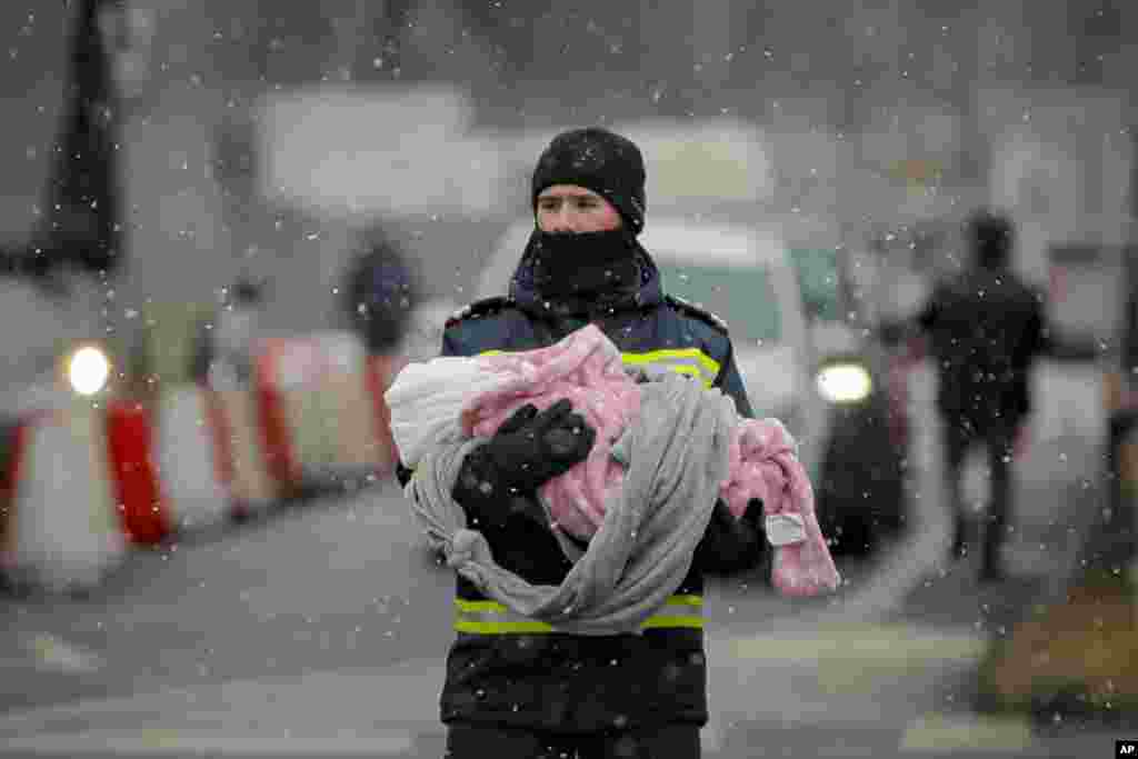 A firefighter holds the baby of a refugee fleeing the conflict from neighboring Ukraine at the Romanian-Ukrainian border, in Siret, Romania.